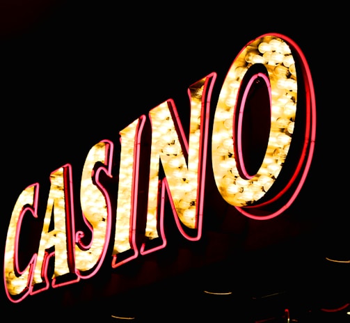 Brightly illuminated letters spell out 'CASINO' with glowing yellow bulbs and red outlines against a dark background.